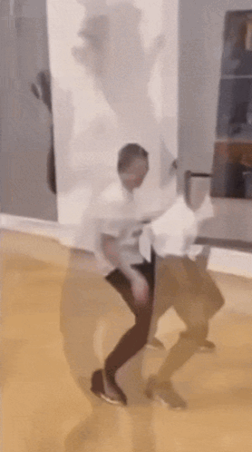 A Man In A White Shirt Is Dancing In A Room With His Shadow Behind Him GIF