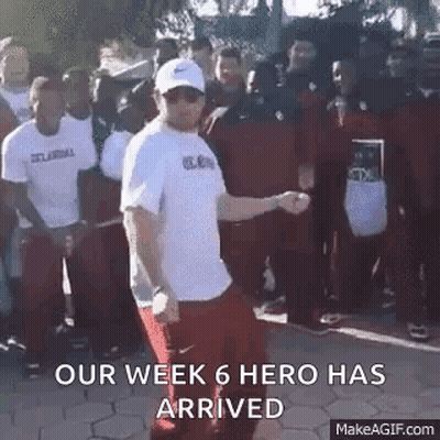 A Man In A White Shirt Is Dancing In Front Of A Crowd Of People With The Words `` Our Week 6 Hero Has Arrived '' . GIF