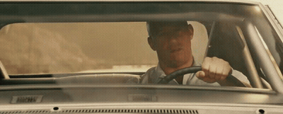 A Man In A White Shirt Is Driving A Car With A License Plate That Says ' Bmw ' GIF