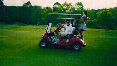 A Man In A White Shirt Is Driving A Red Yamaha Golf Cart GIF