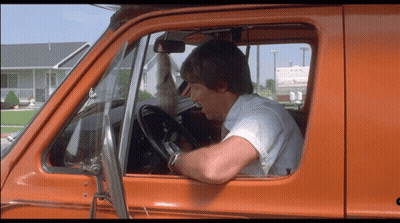A Man In A White Shirt Is Driving An Orange Truck GIF