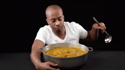 A Man In A White Shirt Is Eating A Large Pot Of Soup With A Ladle GIF