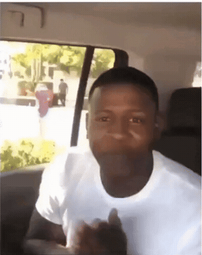 A Man In A White Shirt Is Giving A Thumbs Up In A Car GIF