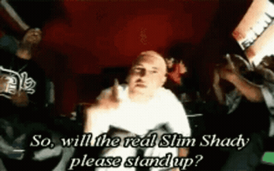 A Man In A White Shirt Is Giving The Middle Finger While Sitting In Front Of A Crowd . GIF