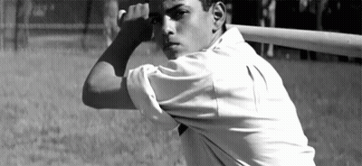 A Man In A White Shirt Is Holding A Baseball Bat Over His Head GIF
