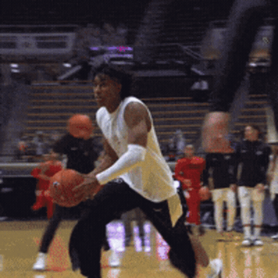 A Man In A White Shirt Is Holding A Basketball On A Court GIF