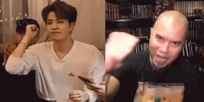 A Man In A White Shirt Is Holding A Cell Phone Next To A Man In A Black Shirt GIF