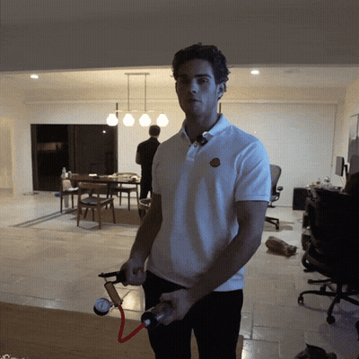 A Man In A White Shirt Is Holding A Hose In His Hand GIF