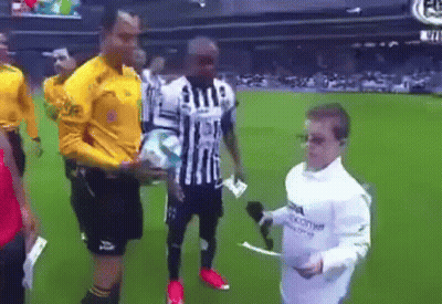 A Man In A White Shirt Is Holding A Microphone And Talking To A Soccer Player On A Field . GIF