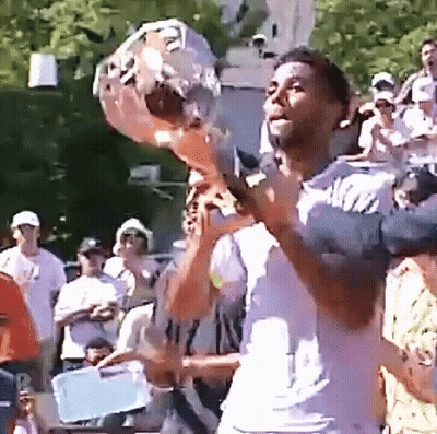 A Man In A White Shirt Is Holding A Microphone In Front Of A Crowd GIF