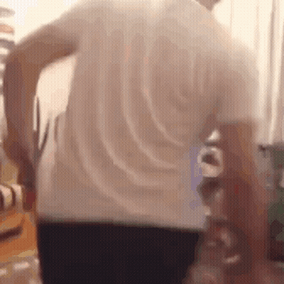 A Man In A White Shirt Is Holding A Pair Of Scissors In His Hand . GIF