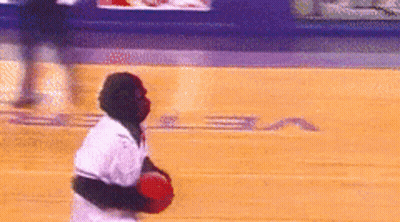 A Man In A White Shirt Is Holding A Red Ball On A Basketball Court With The Letter S On It GIF