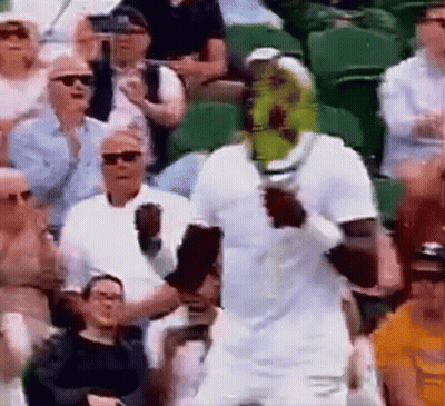 A Man In A White Shirt Is Holding A Tennis Racket In Front Of A Crowd Of People . GIF