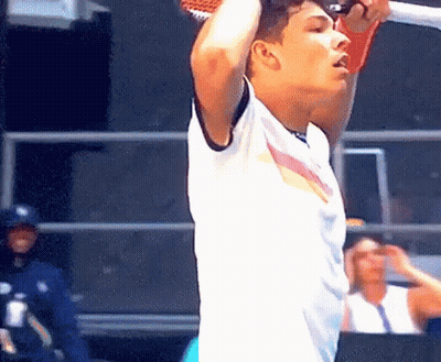 A Man In A White Shirt Is Holding A Tennis Racquet Above His Head GIF