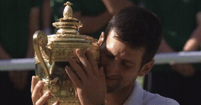A Man In A White Shirt Is Holding A Trophy GIF
