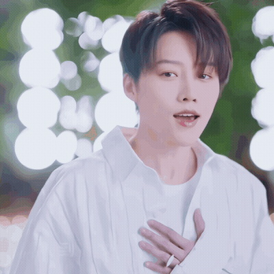 A Man In A White Shirt Is Holding His Hands To His Chest GIF