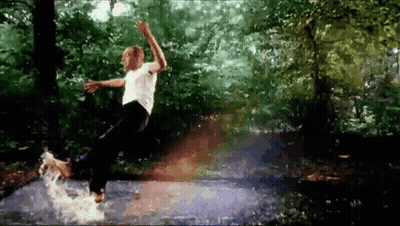 A Man In A White Shirt Is Jumping In A Puddle Of Water GIF