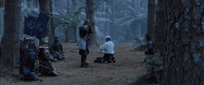 A Man In A White Shirt Is Kneeling Down Next To A Man In Armor With A Sword GIF