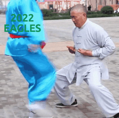 A Man In A White Shirt Is Kneeling Down Next To Another Man In A Blue Shirt With 2022 Eagles Written On The Top GIF