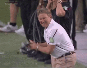 A Man In A White Shirt Is Kneeling Down On A Field . GIF