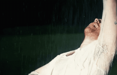 A Man In A White Shirt Is Laughing In The Rain GIF