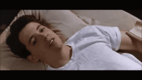 A Man In A White Shirt Is Laying In Bed GIF