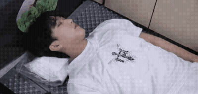 A Man In A White Shirt Is Laying On The Floor With A Pillow . GIF