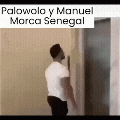 A Man In A White Shirt Is Leaning Against A Wall With The Words Palovolo Y Manuel Morca Senegal Above Him GIF