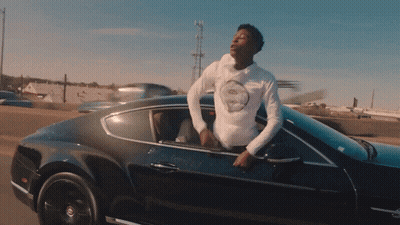 A Man In A White Shirt Is Leaning Out Of The Window Of A Black Car GIF