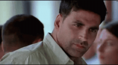 A Man In A White Shirt Is Looking At A Woman In A Crowd . GIF