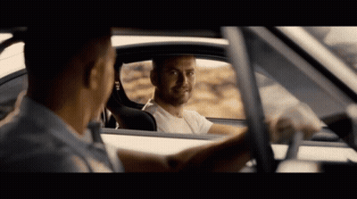 A Man In A White Shirt Is Looking Out The Window Of Another Man 'S Car GIF
