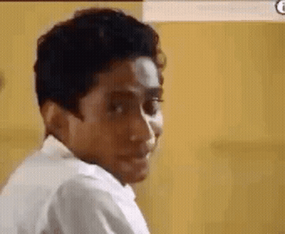 A Man In A White Shirt Is Making A Funny Face And Looking At The Camera . GIF