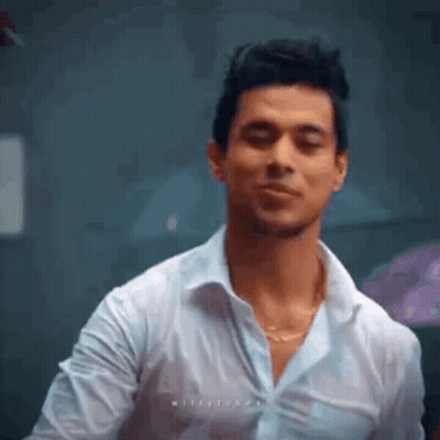 A Man In A White Shirt Is Making A Funny Face While Standing In A Room . GIF