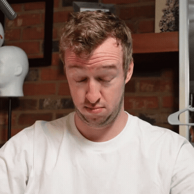 A Man In A White Shirt Is Making A Funny Face With His Eyes Closed GIF
