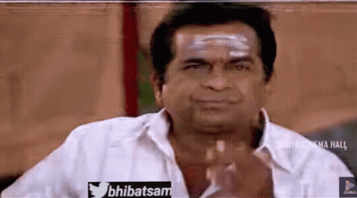 A Man In A White Shirt Is Making A Funny Face With His Hands . GIF