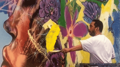 A Man In A White Shirt Is Painting A Colorful Mural On A Wall GIF