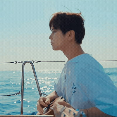 A Man In A White Shirt Is Playing A Guitar In The Ocean GIF