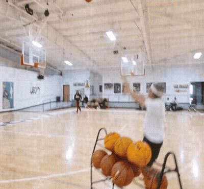A Man In A White Shirt Is Playing Basketball On A Court GIF