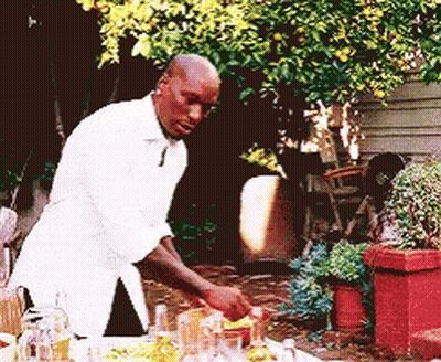 A Man In A White Shirt Is Preparing A Meal Outside GIF