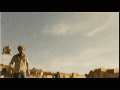 A Man In A White Shirt Is Running In A Field With A Blue Sky Behind Him GIF