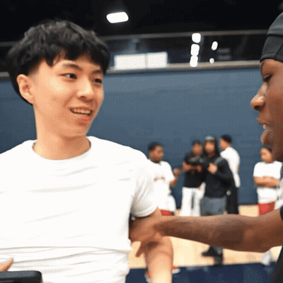 A Man In A White Shirt Is Shaking Hands With Another Man In A Black Hat GIF