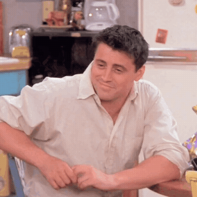 A Man In A White Shirt Is Sitting At A Table GIF