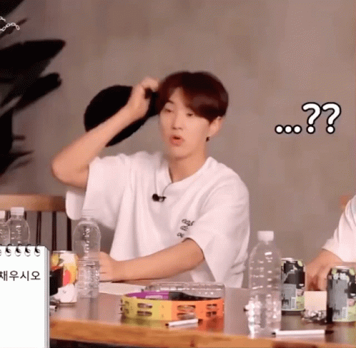 A Man In A White Shirt Is Sitting At A Table With A Bottle Of Water In Front Of Him And A Question Mark Above Him GIF