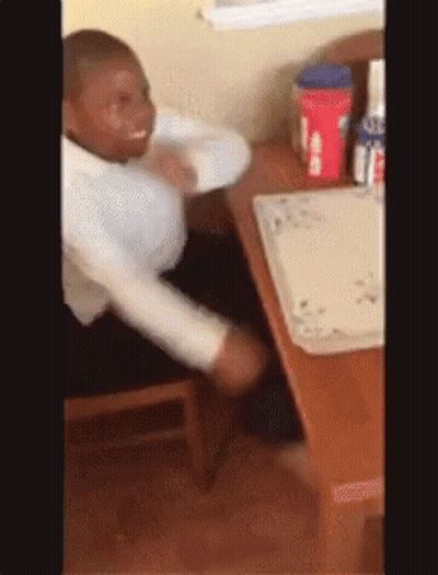 A Man In A White Shirt Is Sitting At A Table With A Coca Cola Bottle In The Background GIF