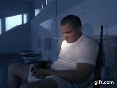 A Man In A White Shirt Is Sitting In A Bathroom With A Gun .. GIF