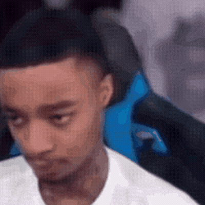 A Man In A White Shirt Is Sitting In A Blue Gaming Chair . GIF