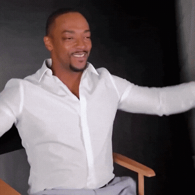 A Man In A White Shirt Is Sitting In A Chair With His Arms Outstretched And Smiling GIF