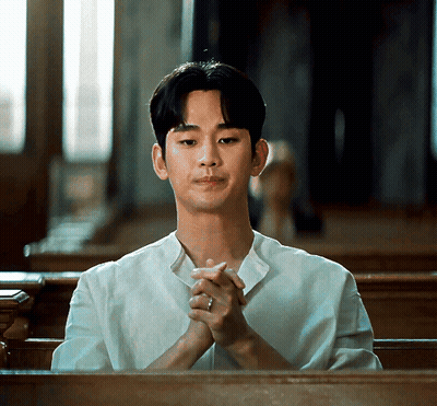 A Man In A White Shirt Is Sitting In A Church With His Hands Folded GIF