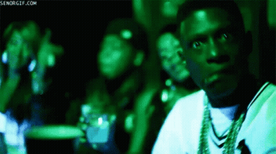 A Man In A White Shirt Is Sitting In A Dark Room With A Green Light Behind Him And The Words Senorgif.com Visible GIF