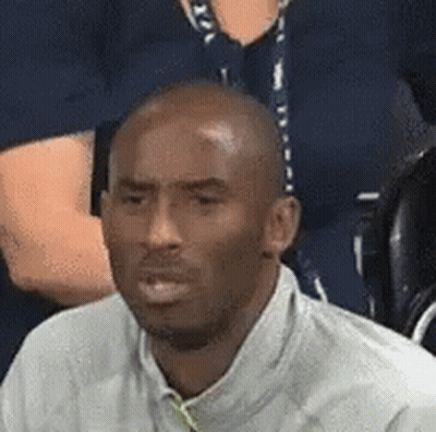 A Man In A White Shirt Is Sitting In A Stadium With A Group Of People . GIF